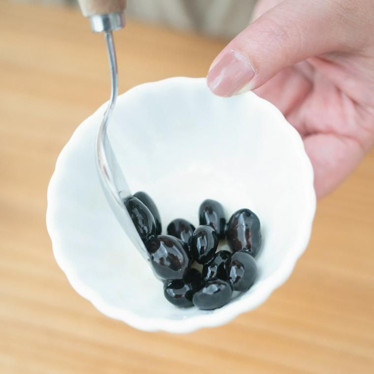 蒸し黒豆にはちみつをあえる様子